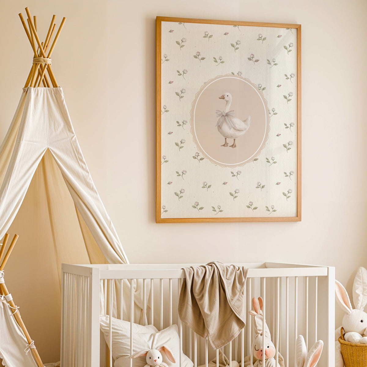 White goose with striped bow in lace oval nursery print in an oak frame above a white crib beside a canvas teepee