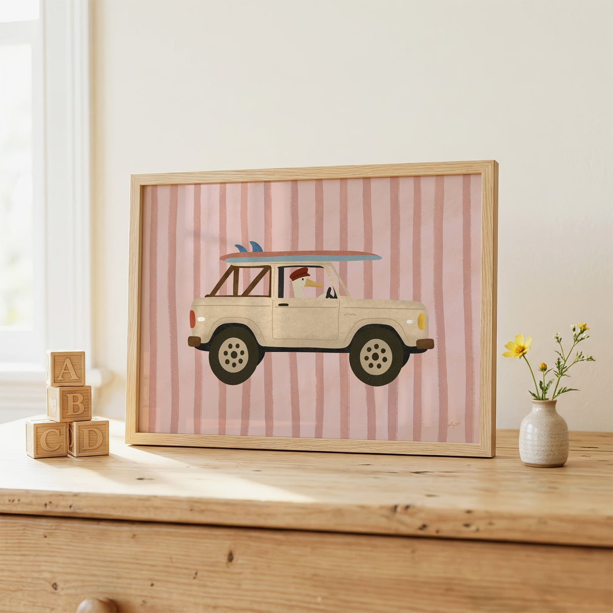 Goose driving cream surf truck nursery print in an oak frame on a wooden dresser beside ABC blocks