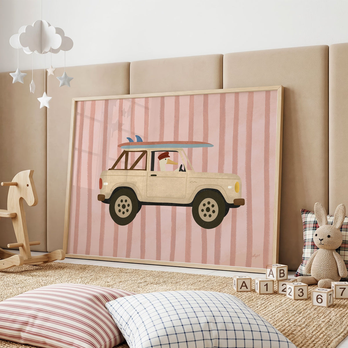 Goose driving cream surf truck nursery print in an oak frame on a padded wall by a wooden rocking horse