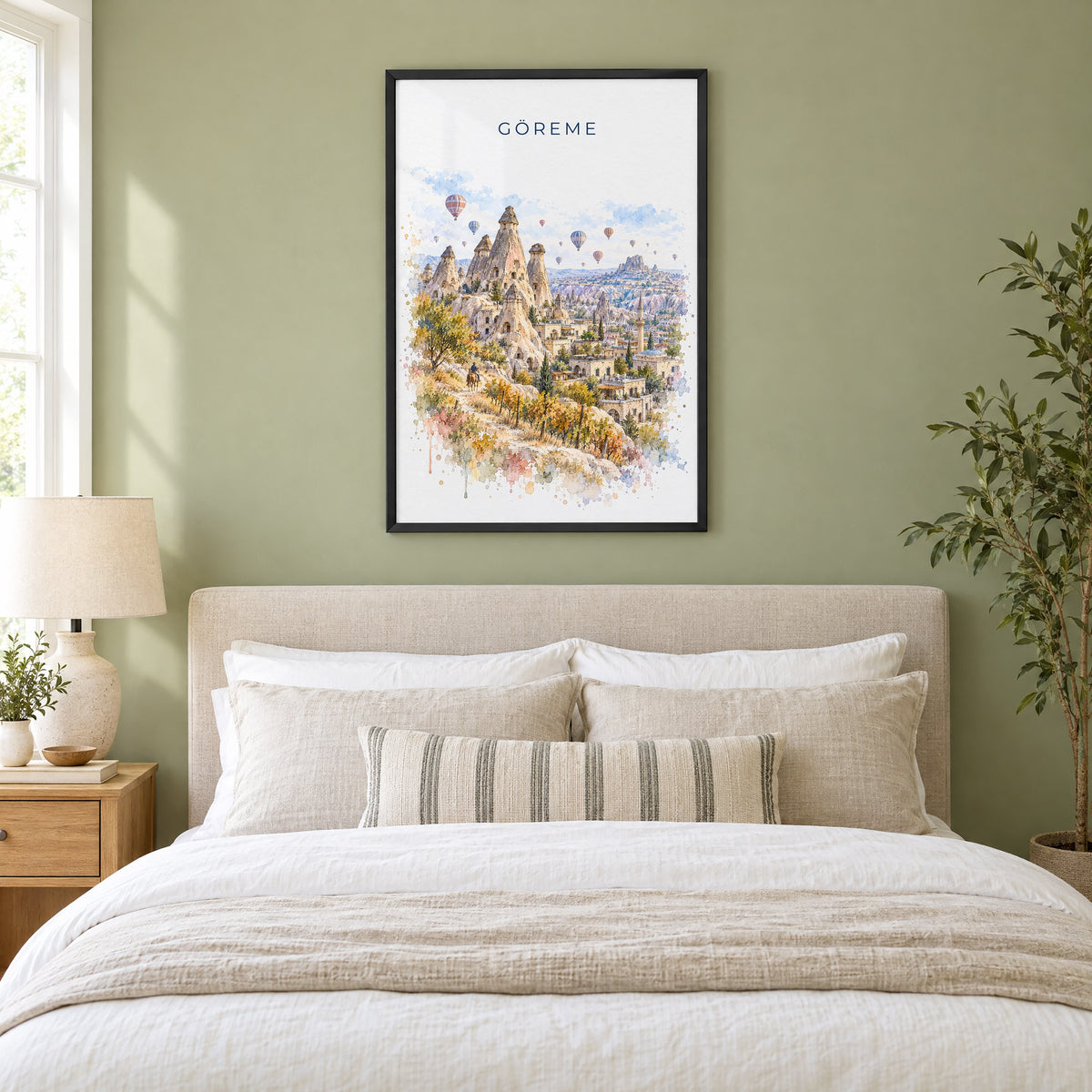 Göreme watercolor print in a black frame above an upholstered headboard in a sage green bedroom