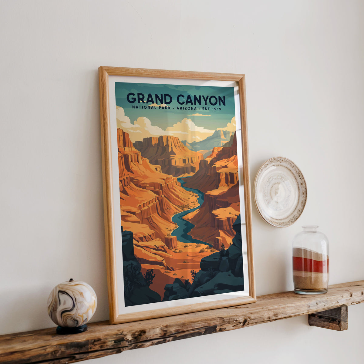 Grand Canyon National Park print in an oak frame on a rustic wood shelf with ceramics and a sand jar
