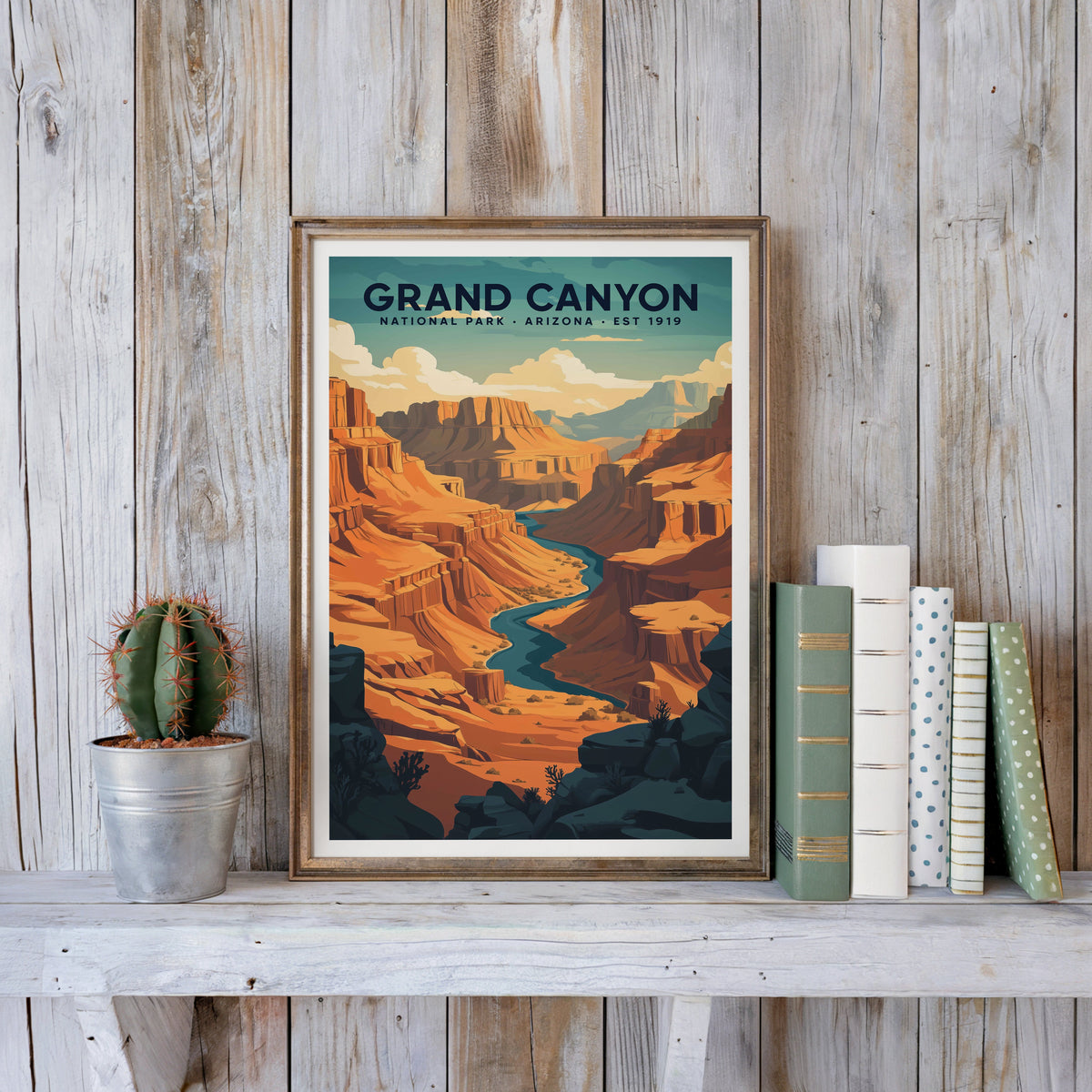 Grand Canyon poster in an antique gold frame against whitewashed farmhouse planks beside books and a cactus
