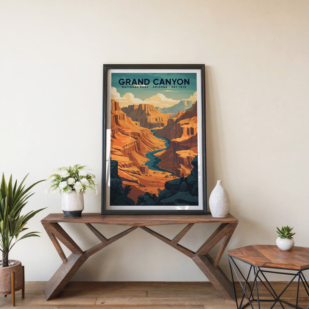 Grand Canyon poster in a black frame on an entryway console table beside white flowers and a yucca