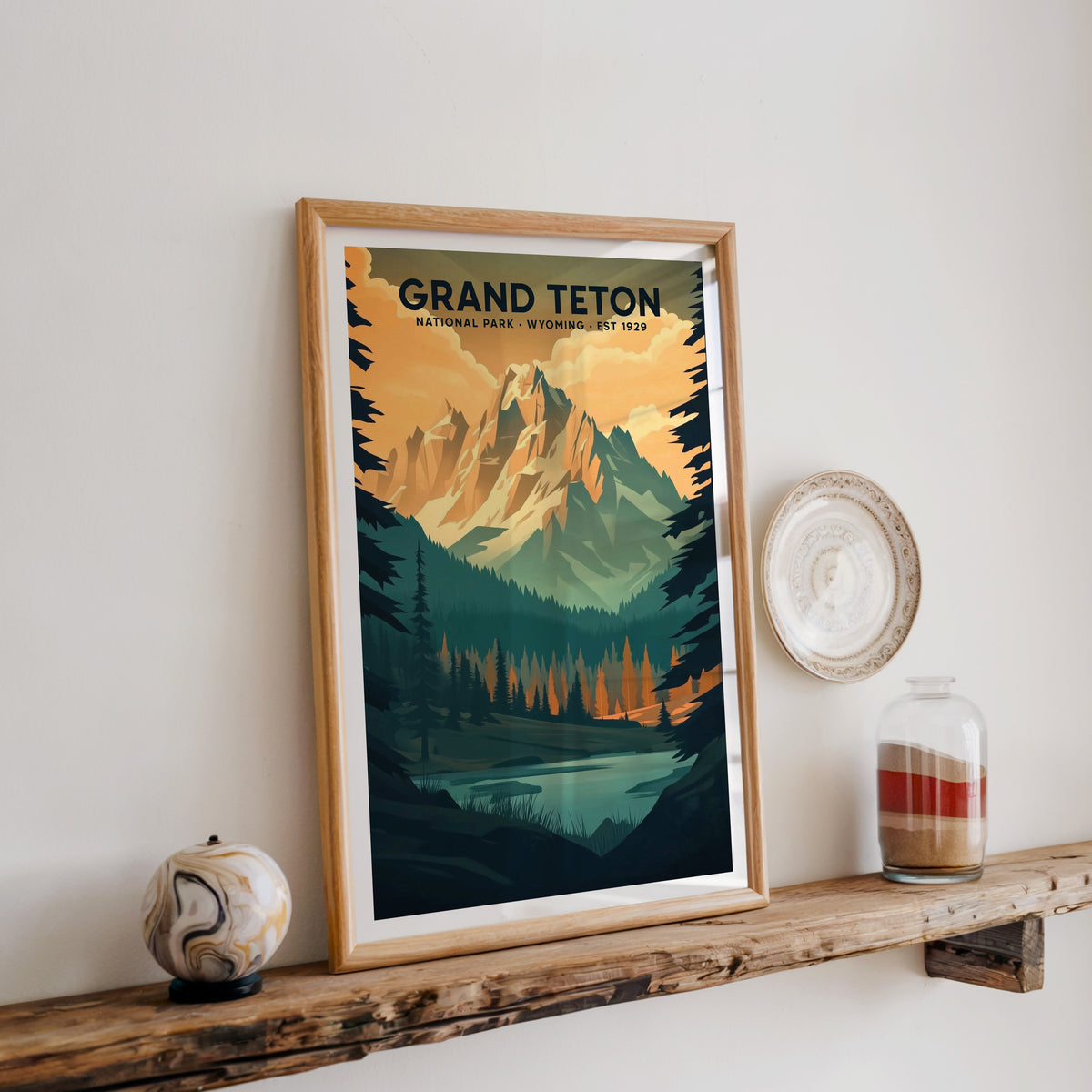 Grand Teton National Park print in an oak frame on a rustic wood shelf with ceramics and a sand jar