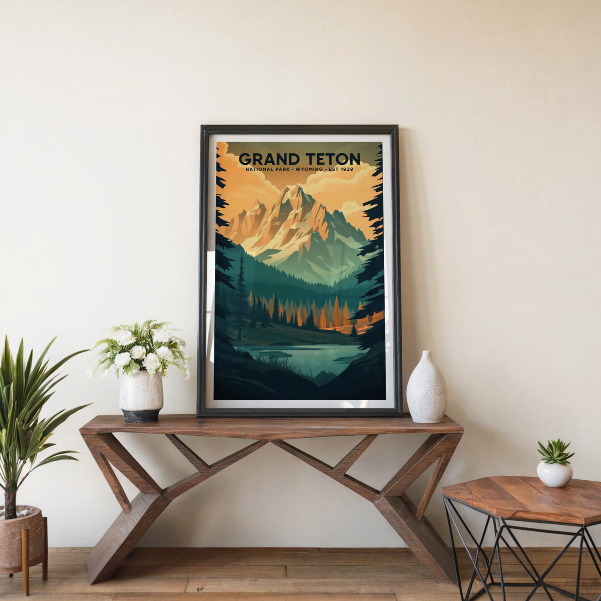 Grand Teton poster in a black frame on an entryway console table beside white flowers and a yucca
