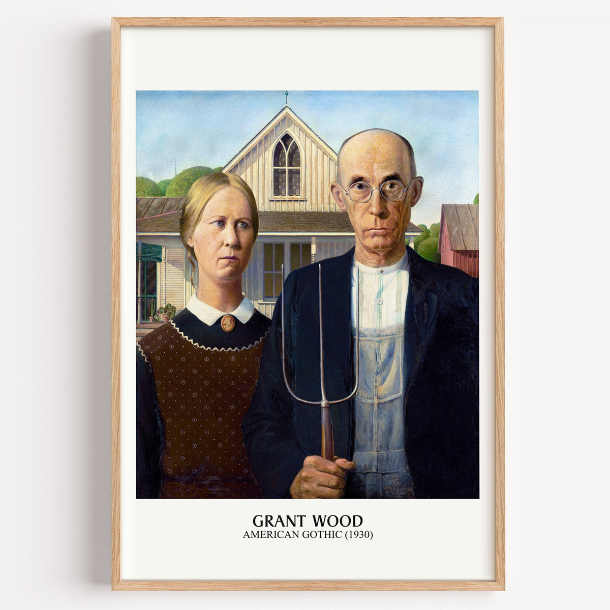 Grant Wood American Gothic print in a light oak frame on a plain white wall