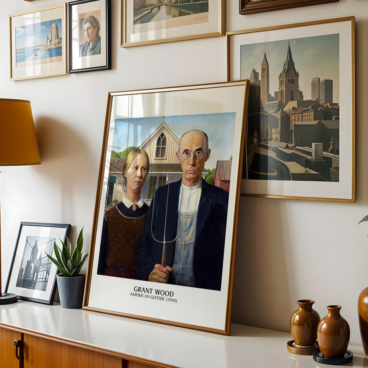 Grant Wood print shown in a gold frame leaning on a sideboard in a gallery wall