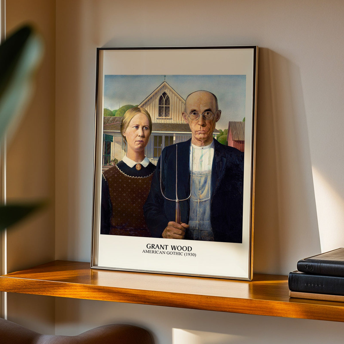 American Gothic print in a black frame on a walnut shelf in evening light