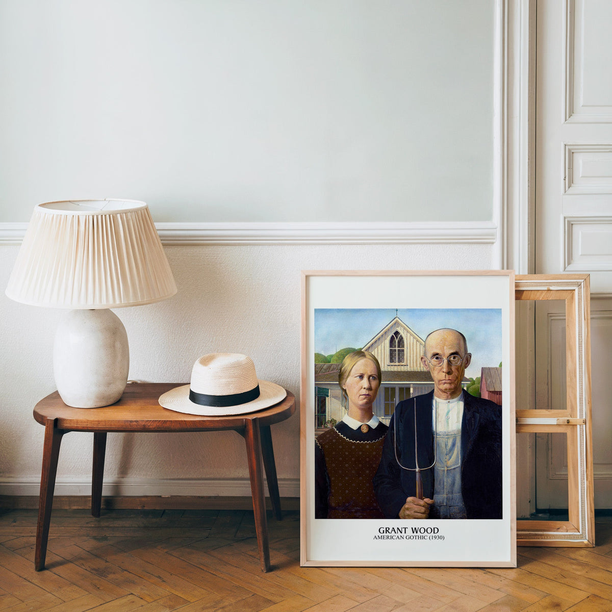 Grant Wood poster in a light wood frame leaning by a bench and panama hat