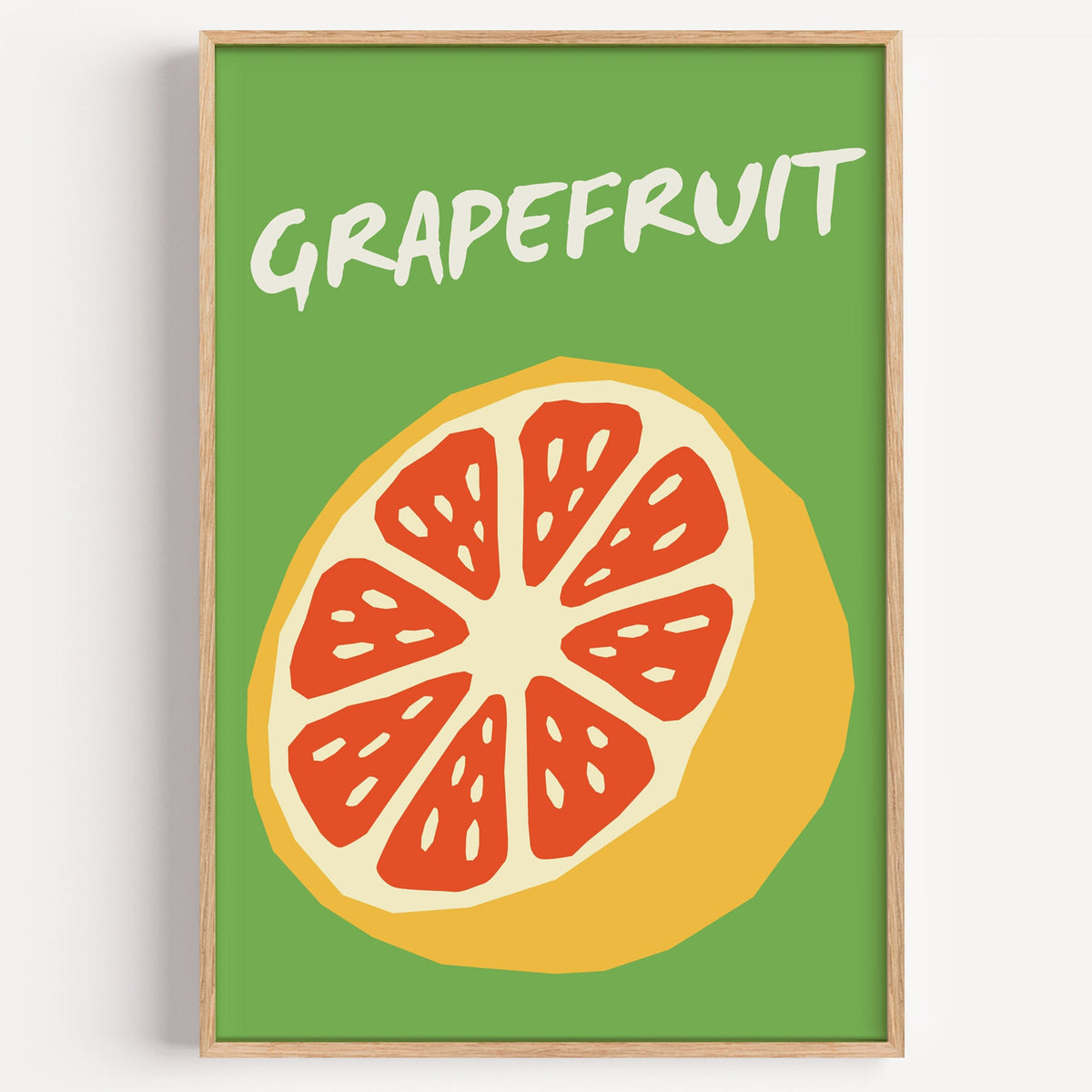 Grapefruit half print in a light oak frame on a plain white wall