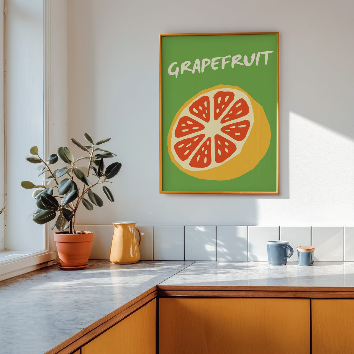 Grapefruit half print shown in a gold frame above a marble counter in a tan kitchen