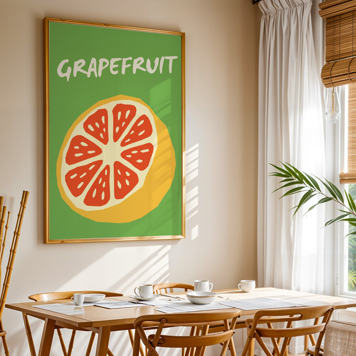 Grapefruit half print shown in a gold frame above a breakfast table by a curtained window