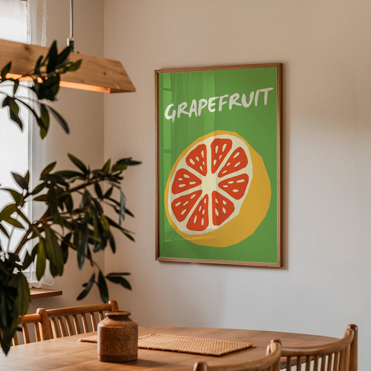 Grapefruit half print in a walnut frame above a dining table with olive branches
