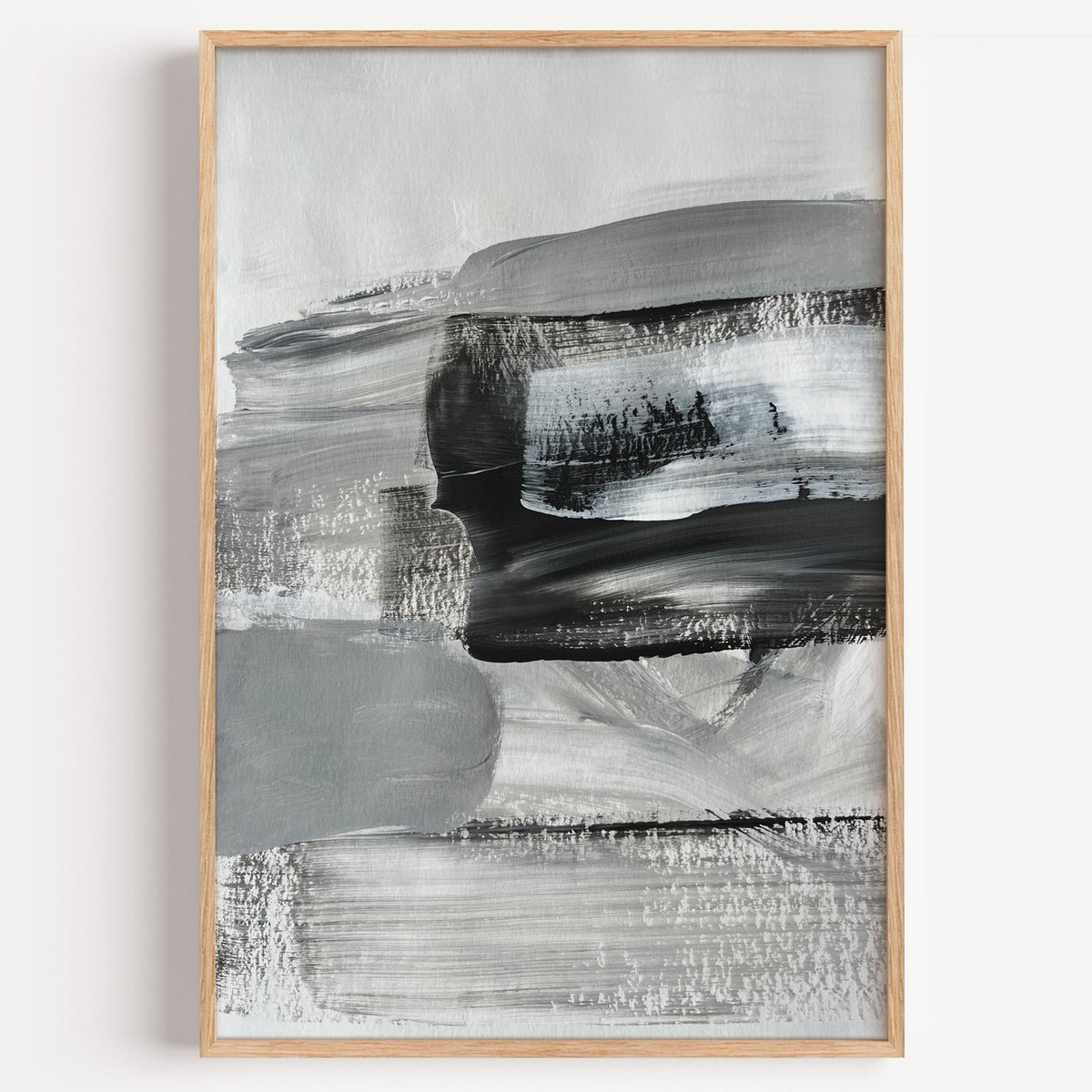Gray and black dry brush layers abstract print in a light oak frame on a plain white wall