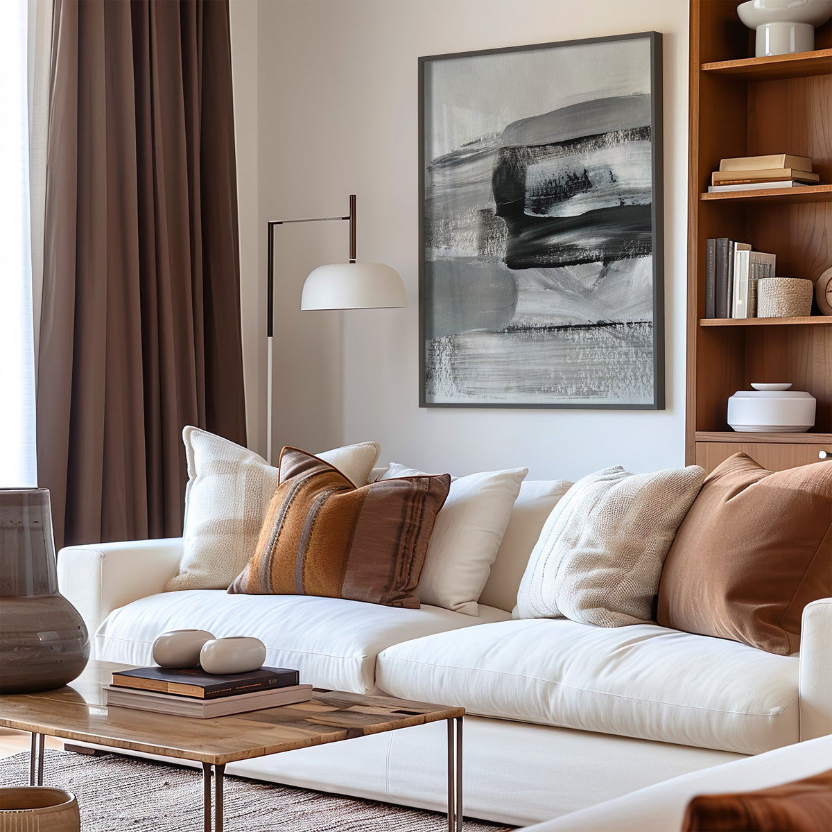 Gray and black dry brush layers abstract print in a black frame above a cream sofa with brown striped pillows