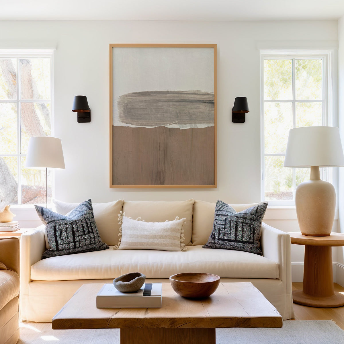Gray brush band over mocha brushstroke print in a light oak frame above a cream sofa between two black wall sconces
