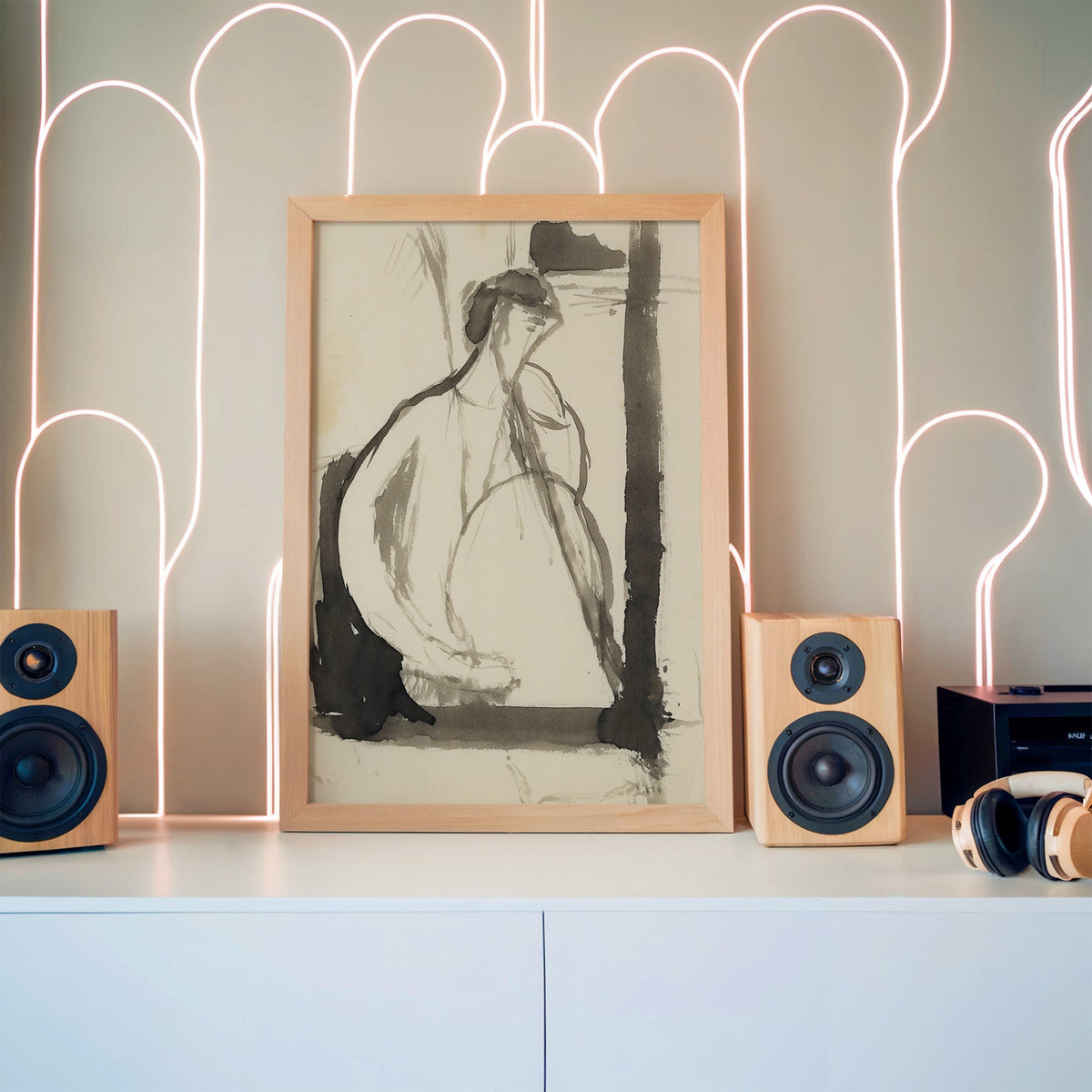 Gray ink seated woman figure sketch print in a pine frame between wooden speakers by a neon arch light wall