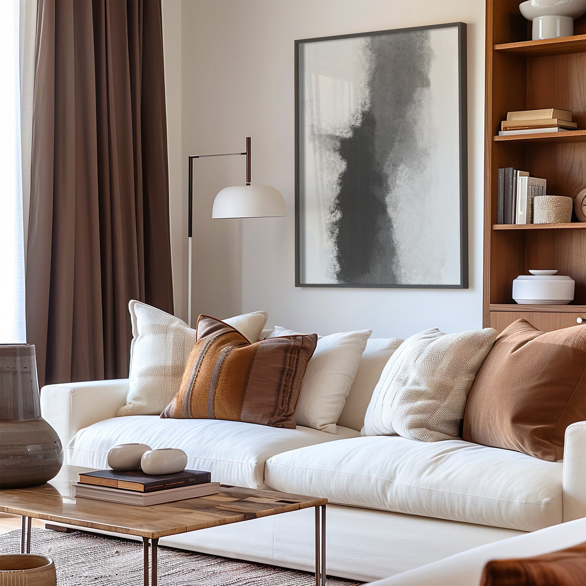 Gray ink smoke column minimalist abstract print in a black frame above a cream sofa with brown striped pillows