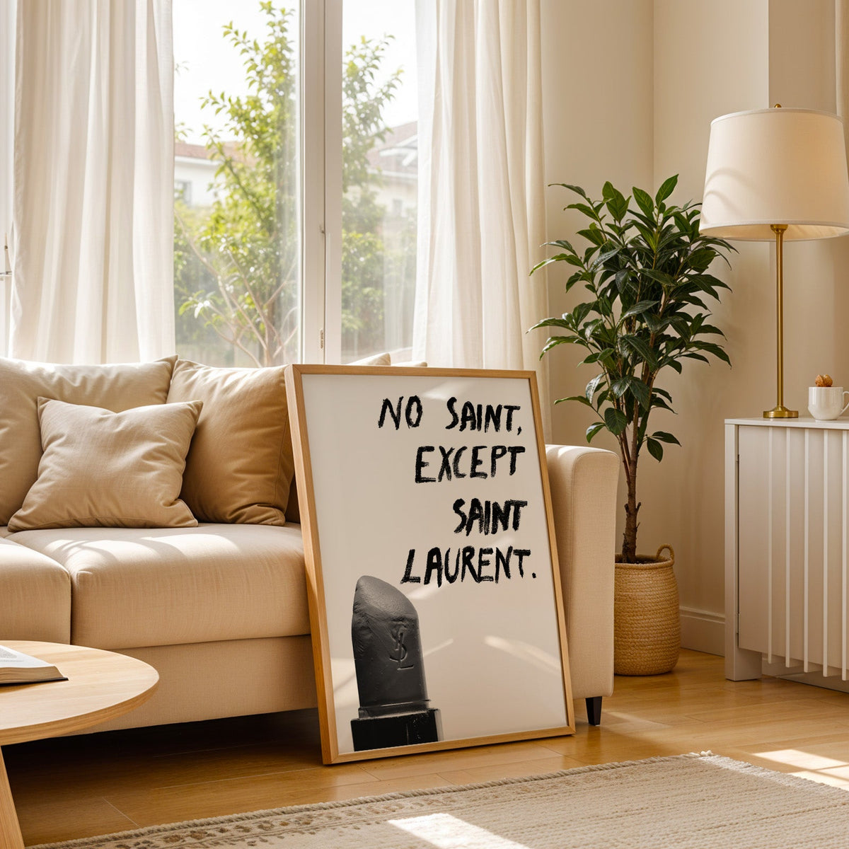 Gray lipstick with black brush lettering quote print in a light oak frame leaning on a cream sofa beside a floor lamp