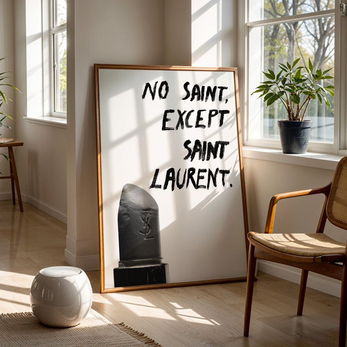 Gray lipstick with black brush lettering quote print in a walnut frame on a wood floor beside a cane chair and sunny window