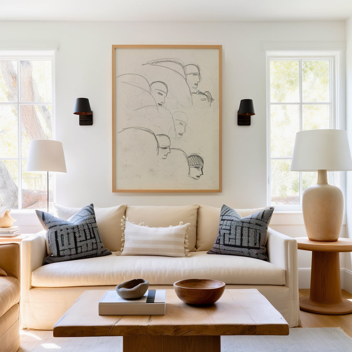 Gray pencil bob hair profiles figure sketch print in a light oak frame above a cream sofa between two black wall sconces
