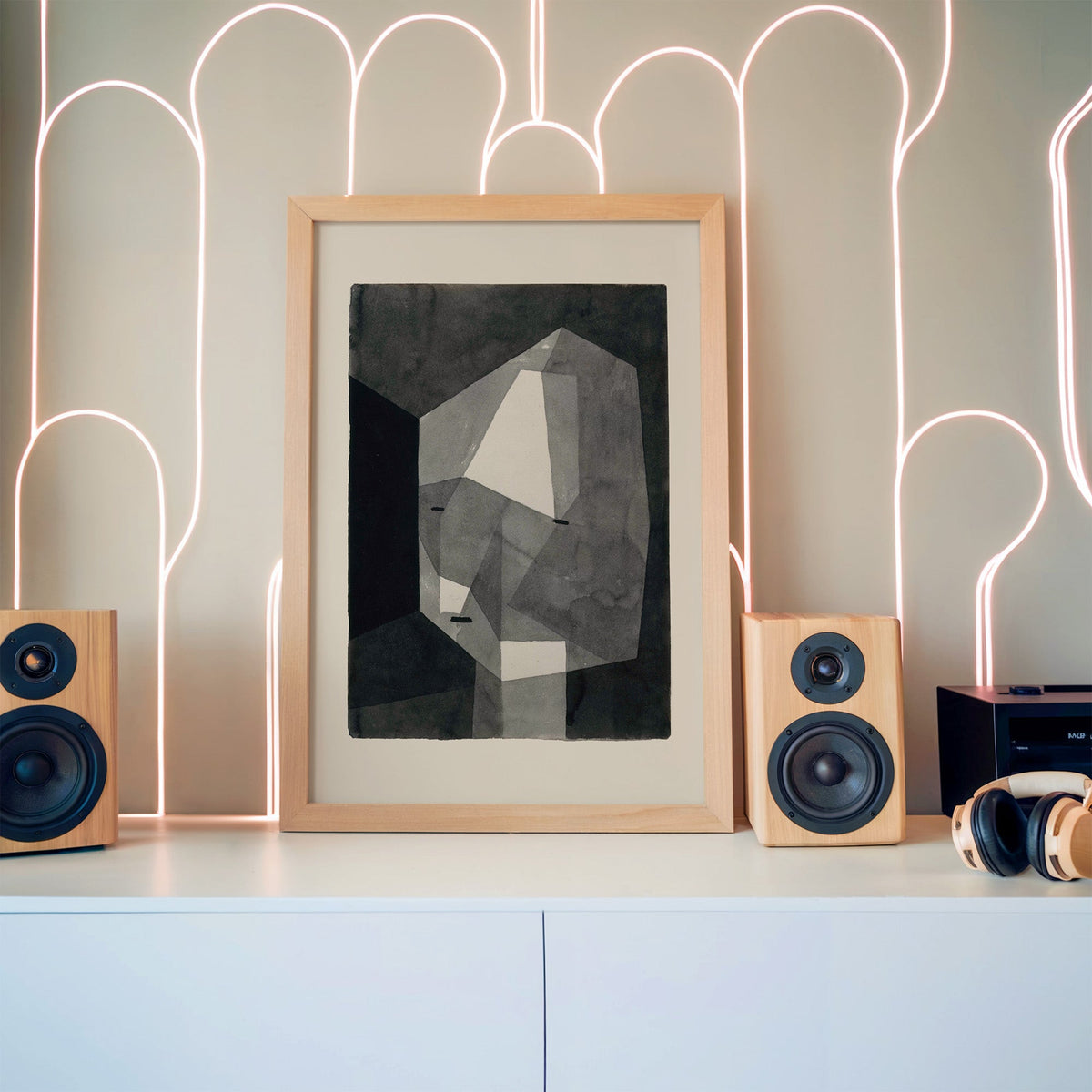 Gray faceted crystal head watercolor abstract print in a pine frame between wooden speakers by a neon arch light wall