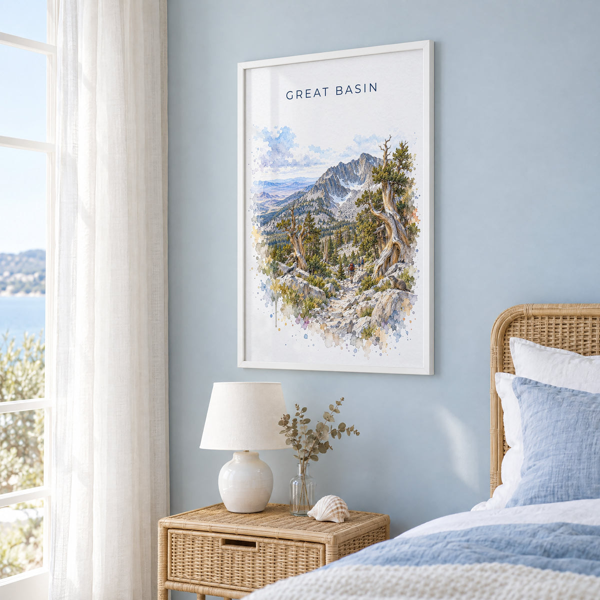 Great Basin National Park watercolor print in a white frame on a pale blue wall beside a rattan bed in a coastal bedroom