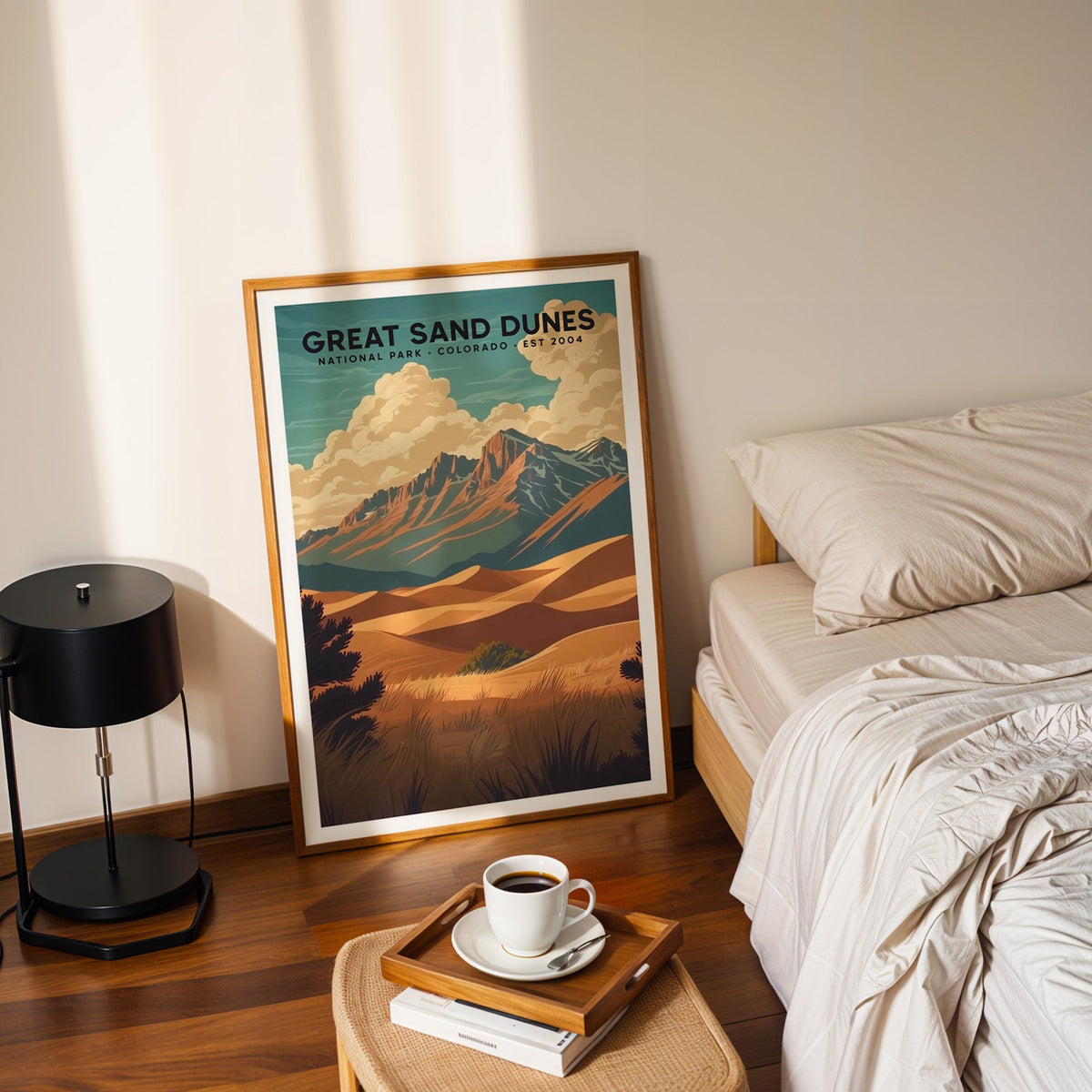 Great Sand Dunes print in an oak frame leaning on a bedroom floor beside the bed and a tray