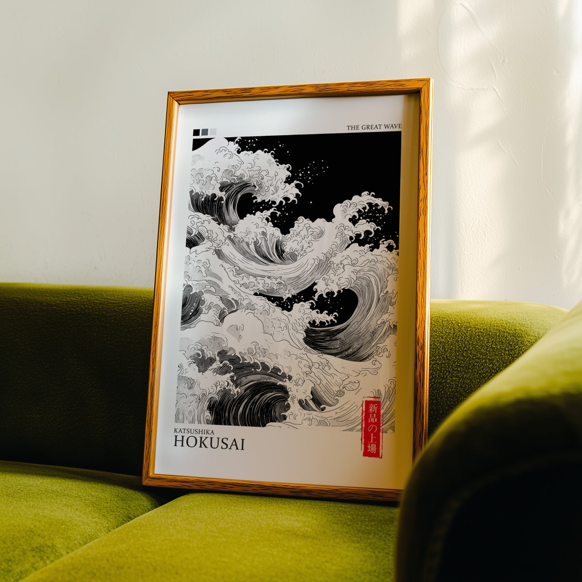 Black and white Great Wave print in an oak frame propped on a green velvet sofa