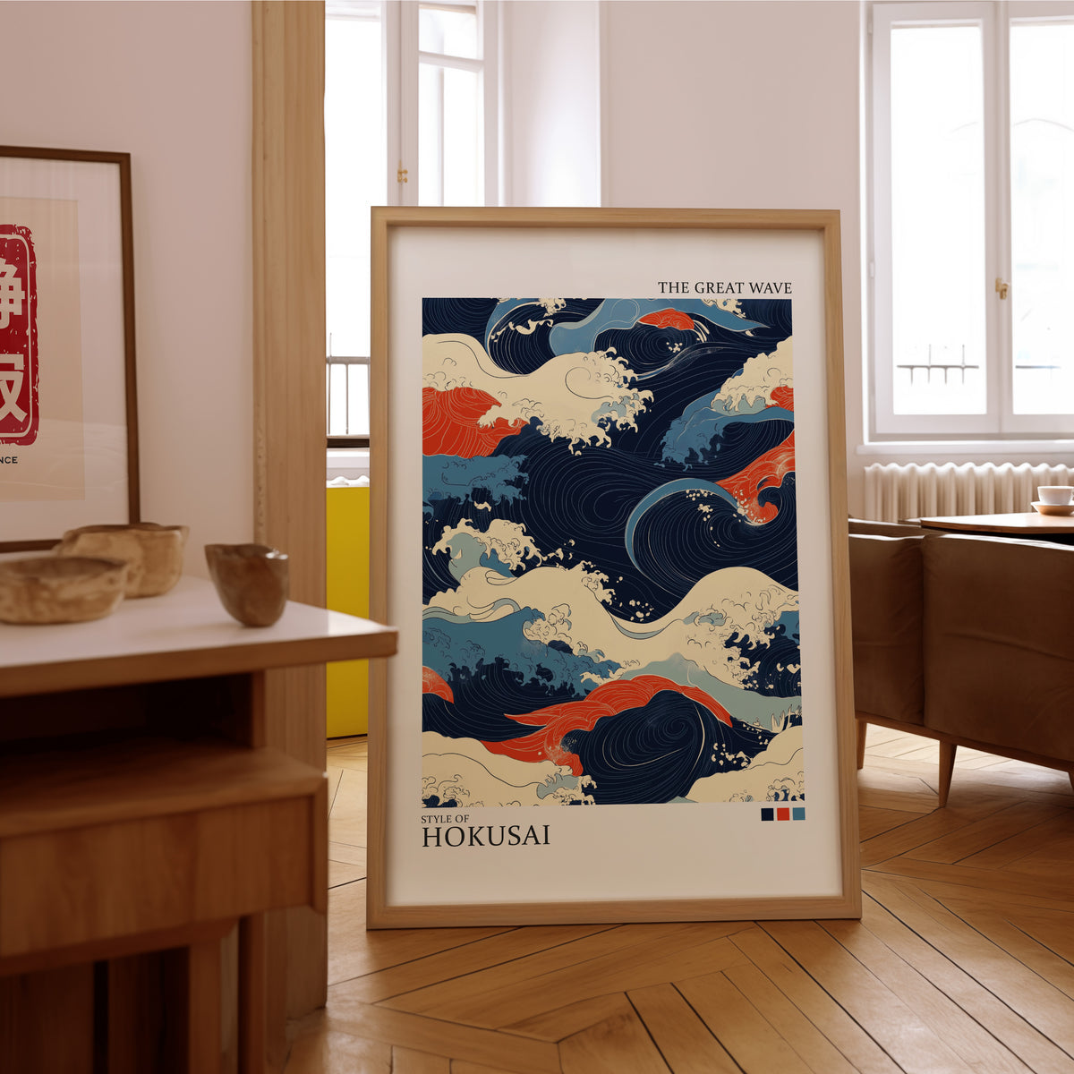Navy and orange Great Wave print in an oak frame on the parquet floor of a sunlit living room