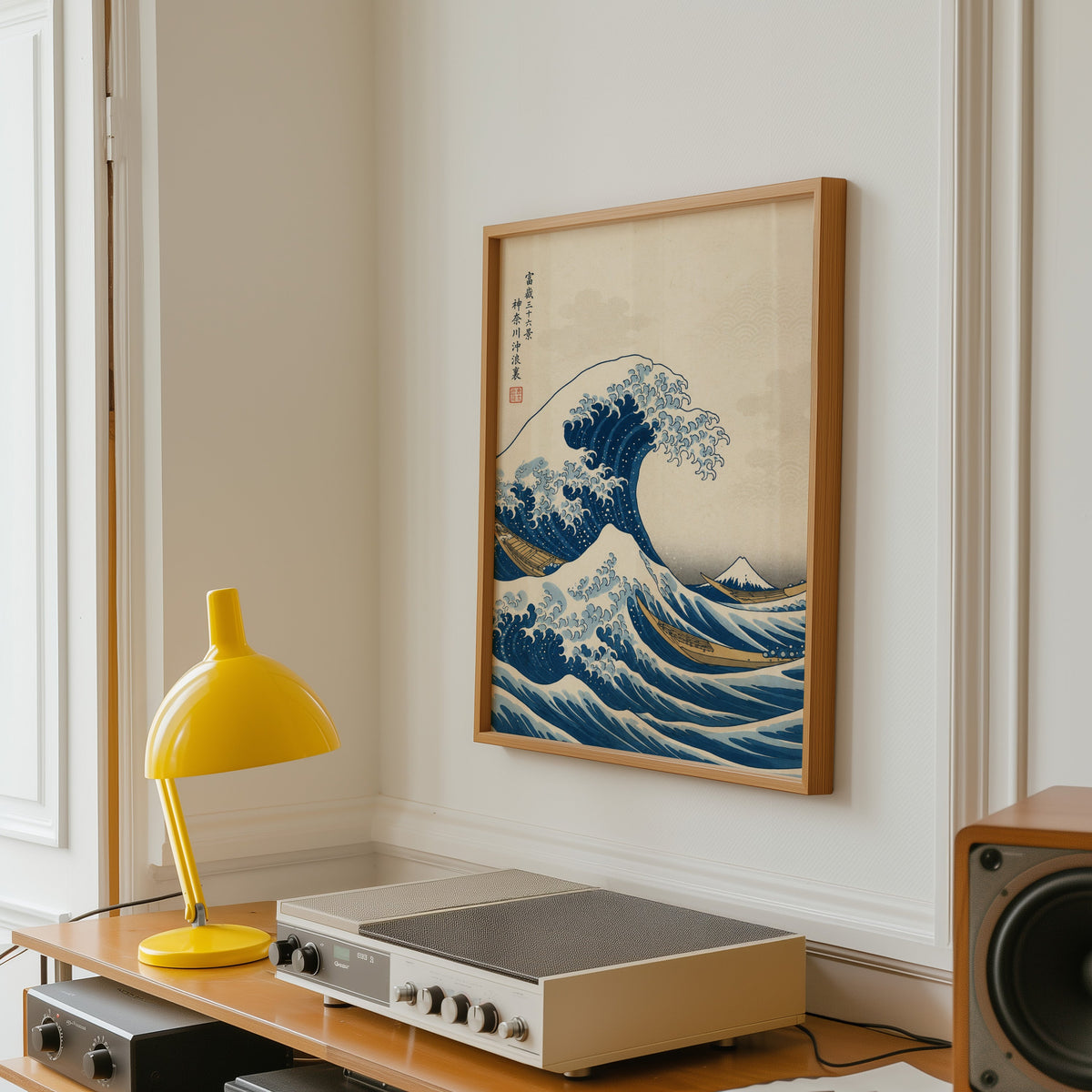 Great Wave off Kanagawa print in an oak frame above a vintage hi-fi shelf with a yellow desk lamp