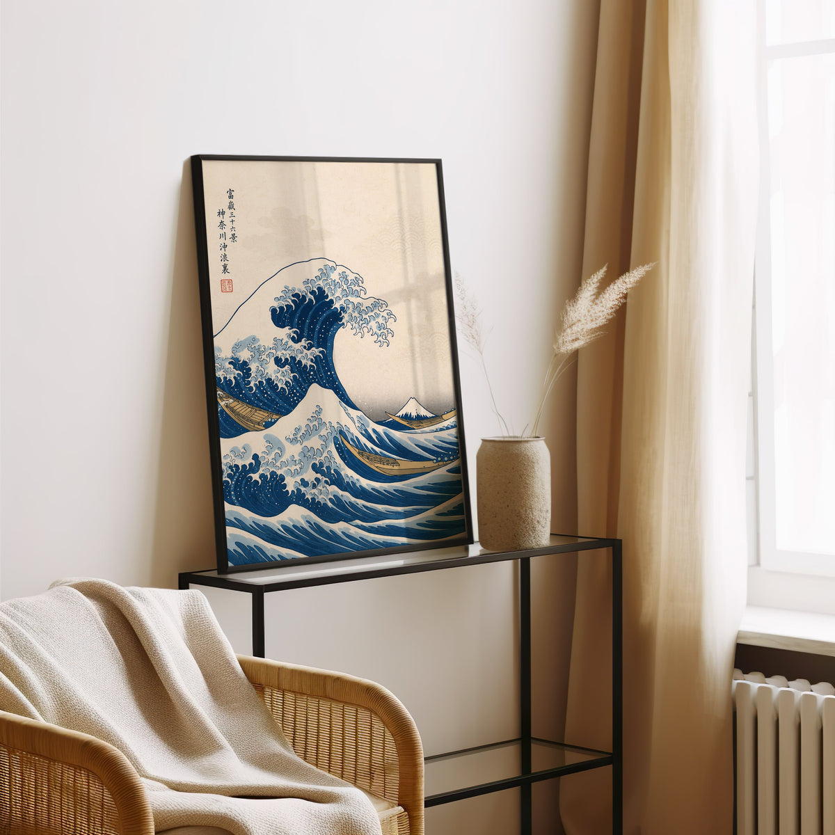 Great Wave off Kanagawa print in a black frame leaning on a glass console beside pampas grass
