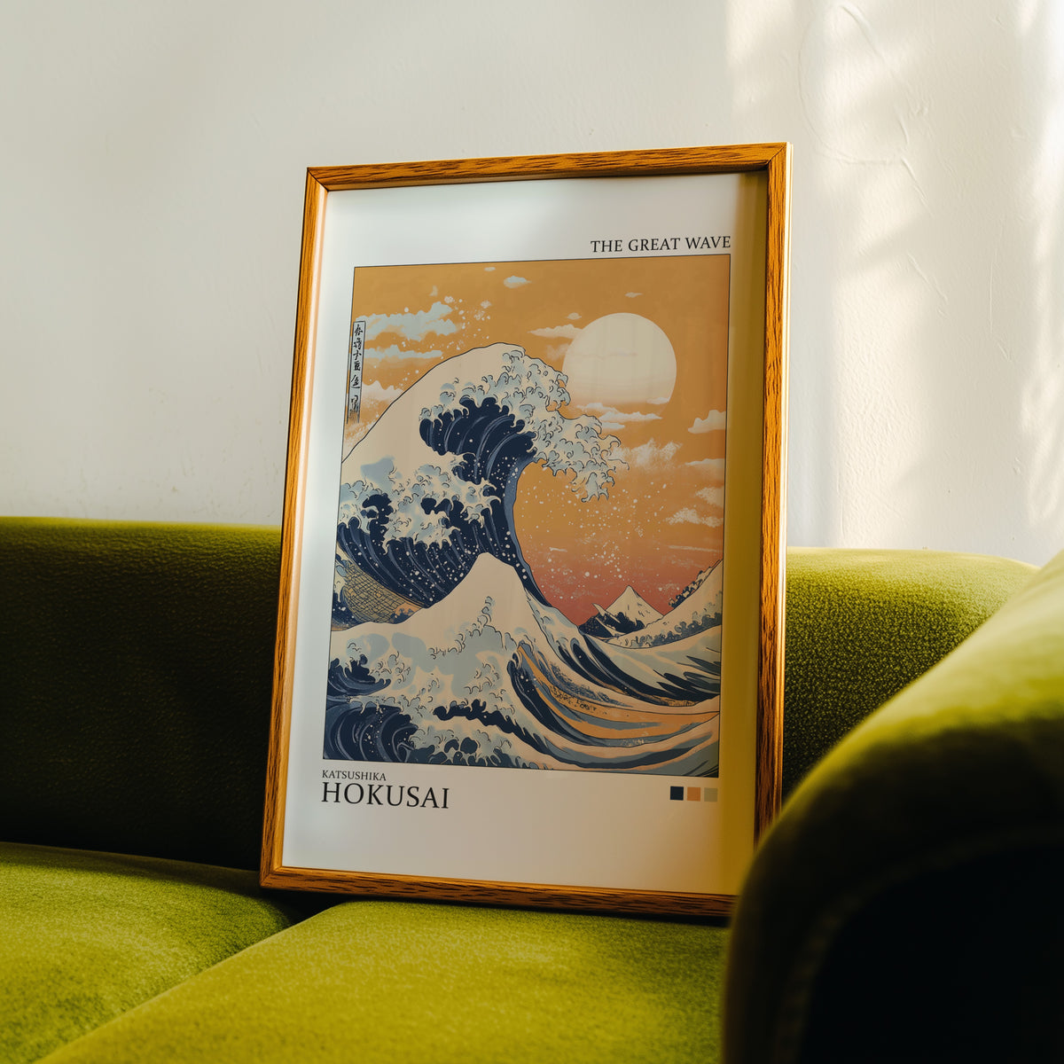 Great Wave under orange sky print in an oak frame propped on a green velvet sofa