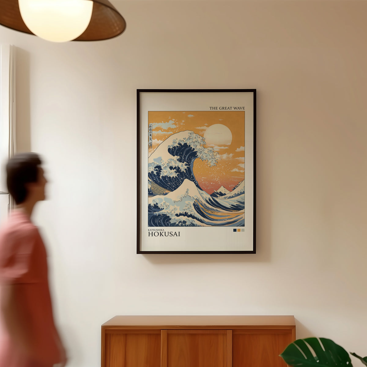 Great Wave under orange sky print in a black frame in a hallway under a rattan pendant