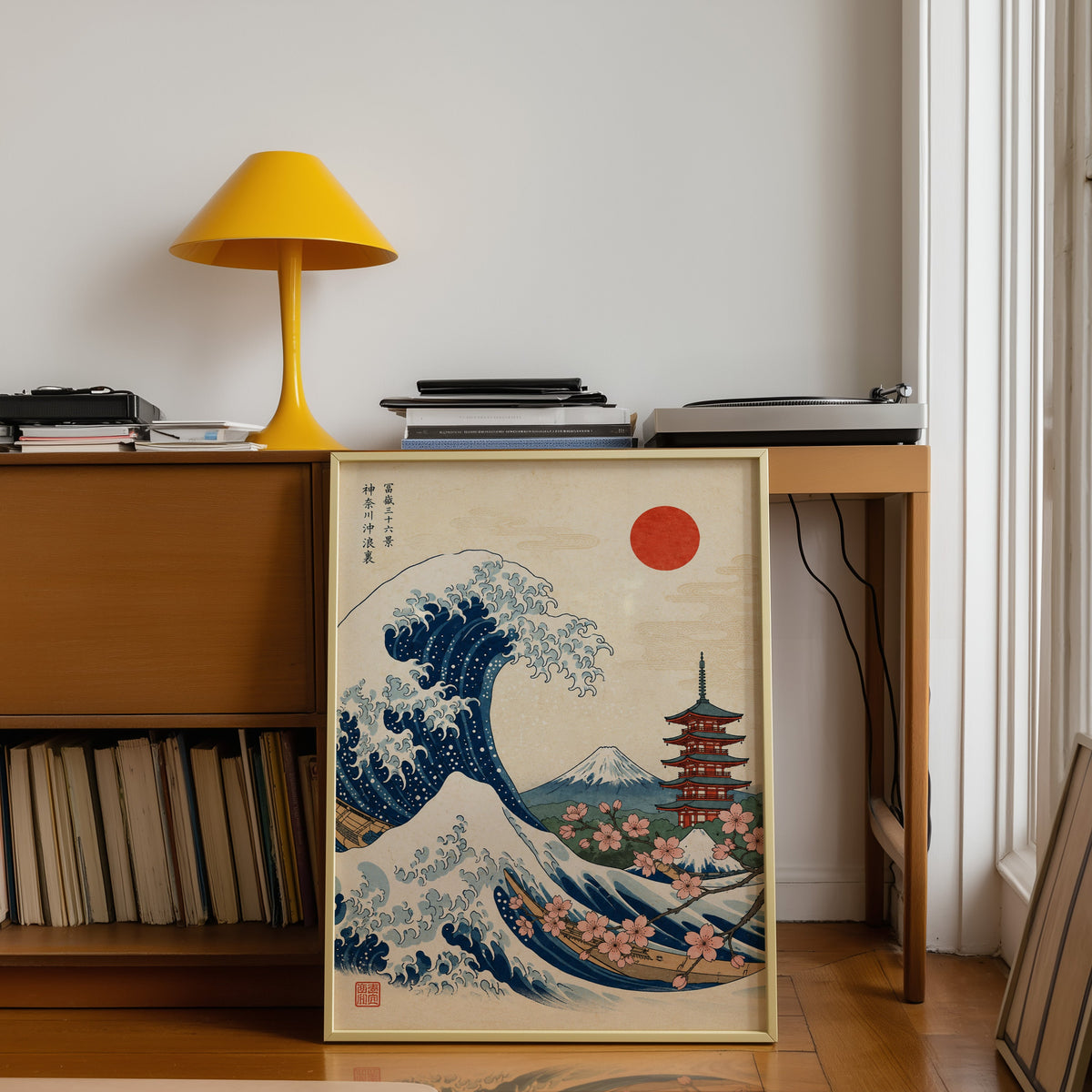Great Wave with pagoda and cherry blossom print shown in a gold frame leaning under a teak desk with a yellow lamp