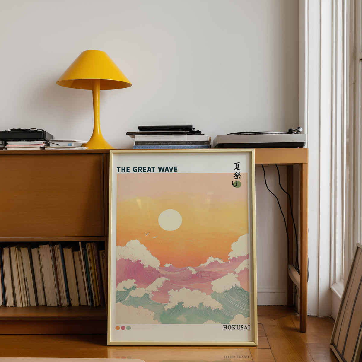 Pastel Great Wave sunset print shown in a gold frame below a teak desk with a yellow lamp