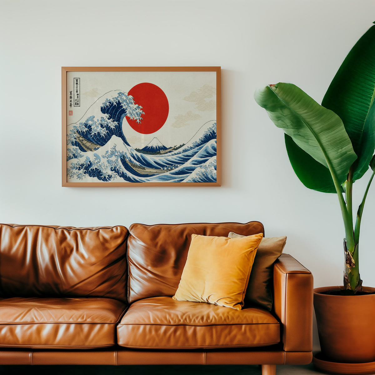 Great Wave with a red sun print in a warm oak frame above a cognac leather sofa with a mustard pillow