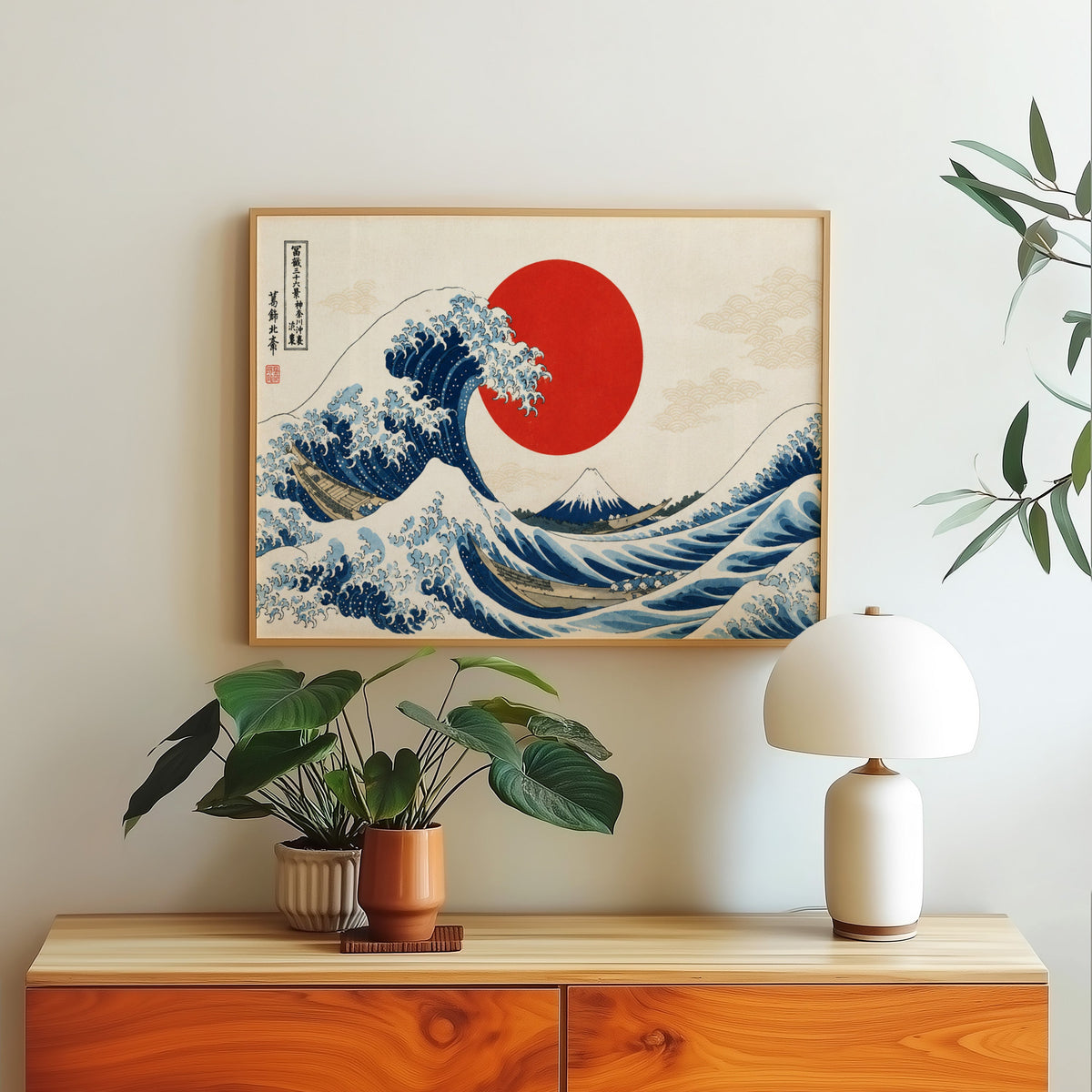 Great Wave with a red sun print in a light oak frame above a wood sideboard with a white dome lamp
