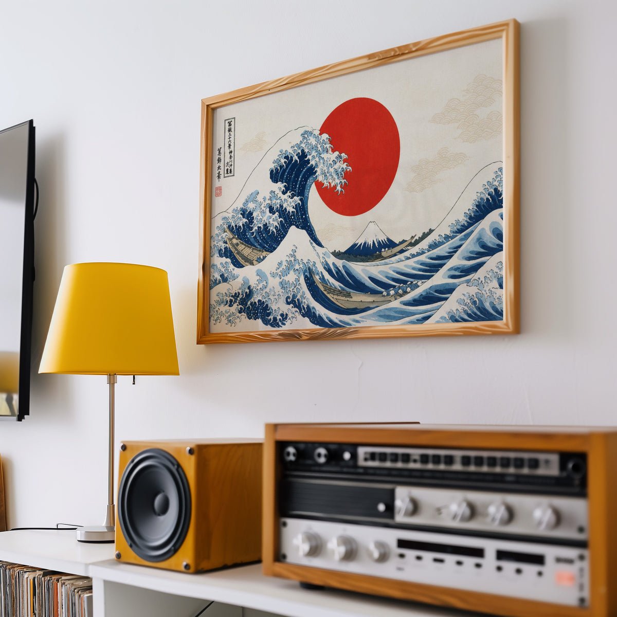 Great Wave with a red sun print in a pine frame above a vintage stereo and a yellow table lamp