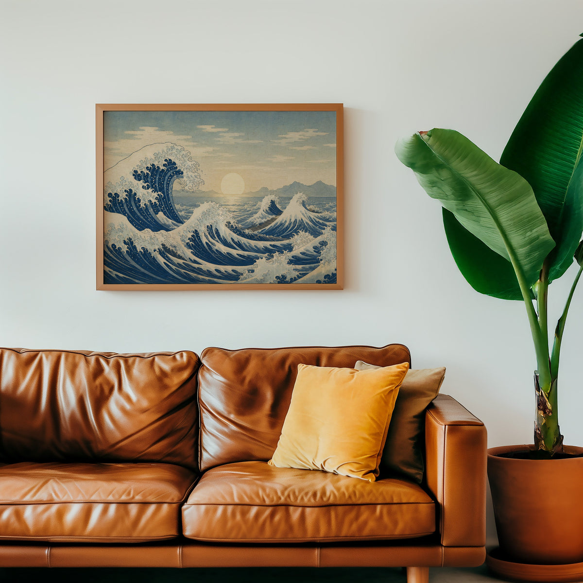 Great wave at sunrise over the sea print in a warm oak frame above a cognac leather sofa with a mustard pillow