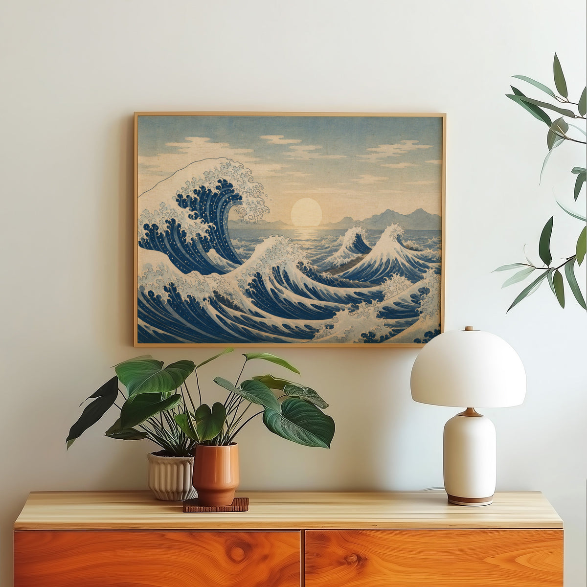 Great wave at sunrise over the sea print in a light oak frame above a wood sideboard with a white dome lamp