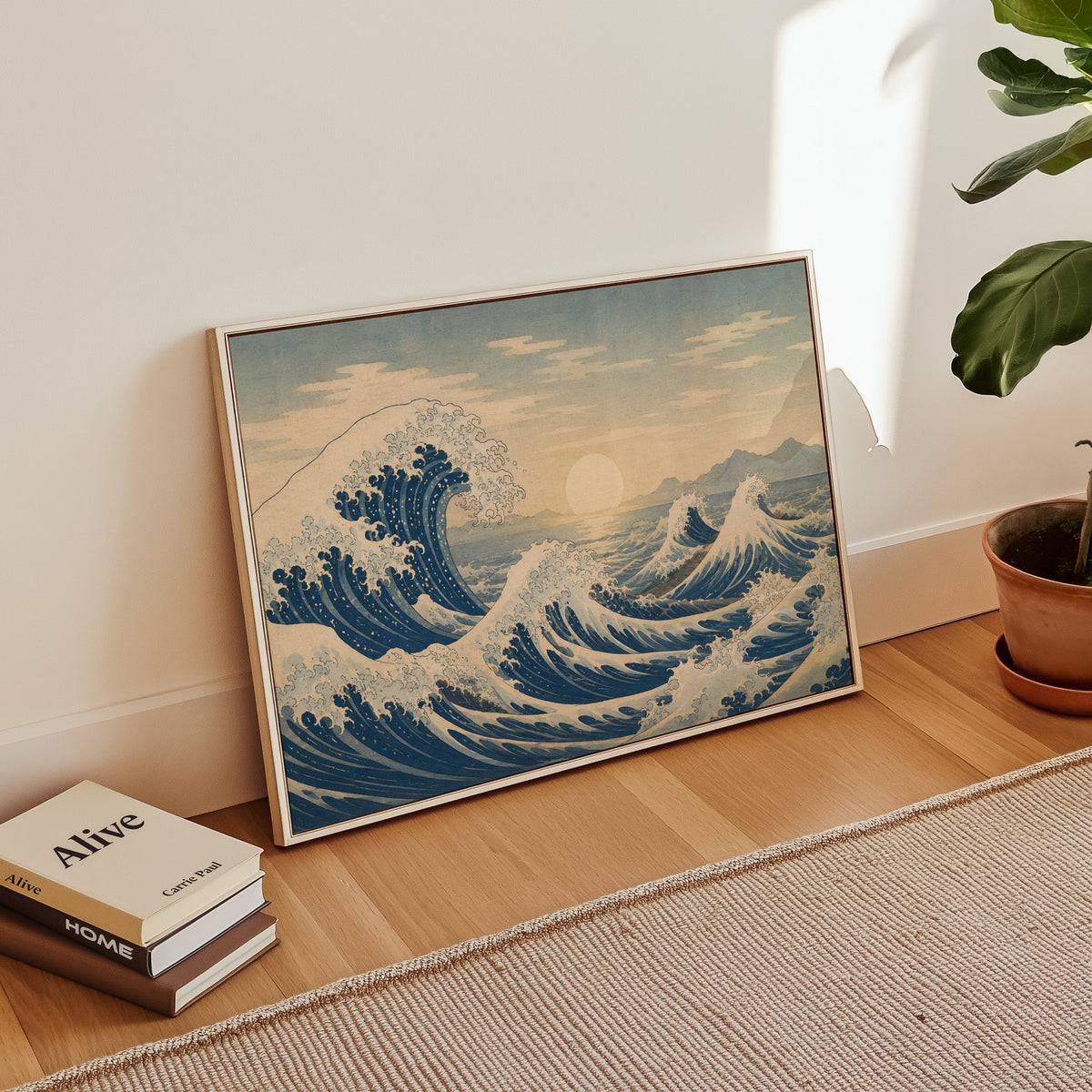 Great wave at sunrise over the sea print in a white floater frame leaning on a wood floor beside stacked books