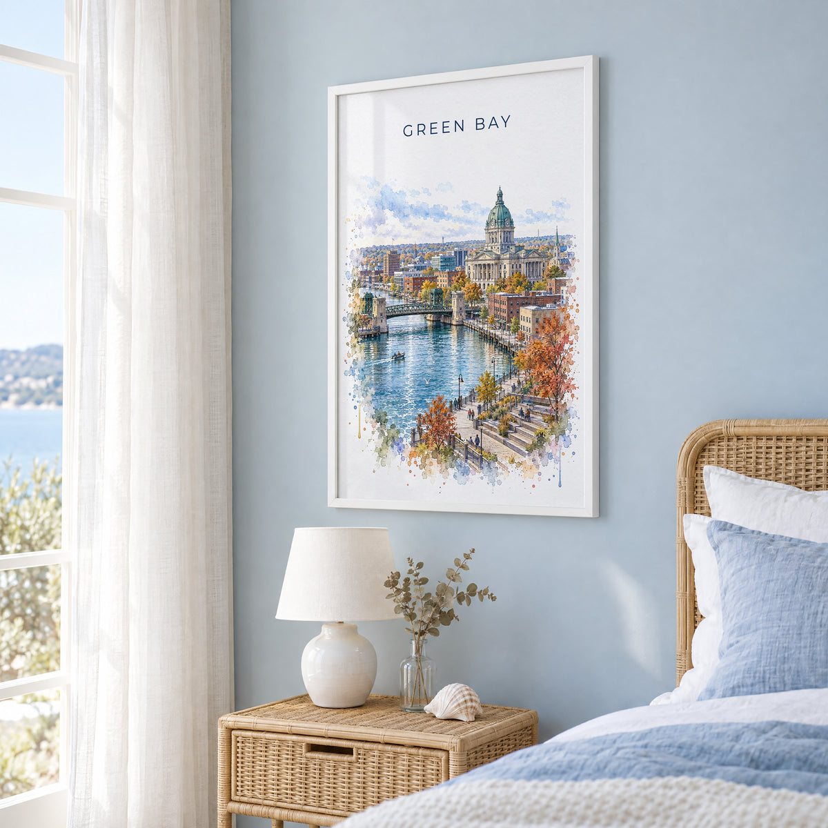 Green Bay watercolor print in a white frame on a pale blue wall beside a rattan bed in a coastal bedroom
