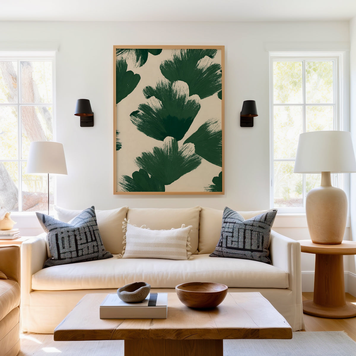 Green brushstroke fan pattern print in a light oak frame above a cream sofa between two black wall sconces