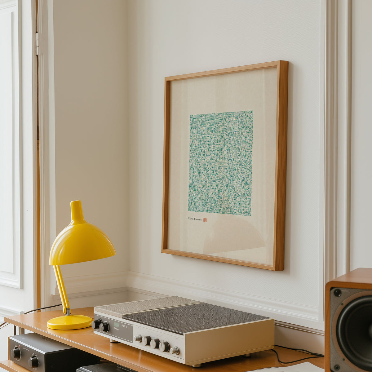 green dot field abstract print in an oak frame above a vintage hi-fi shelf with a yellow desk lamp