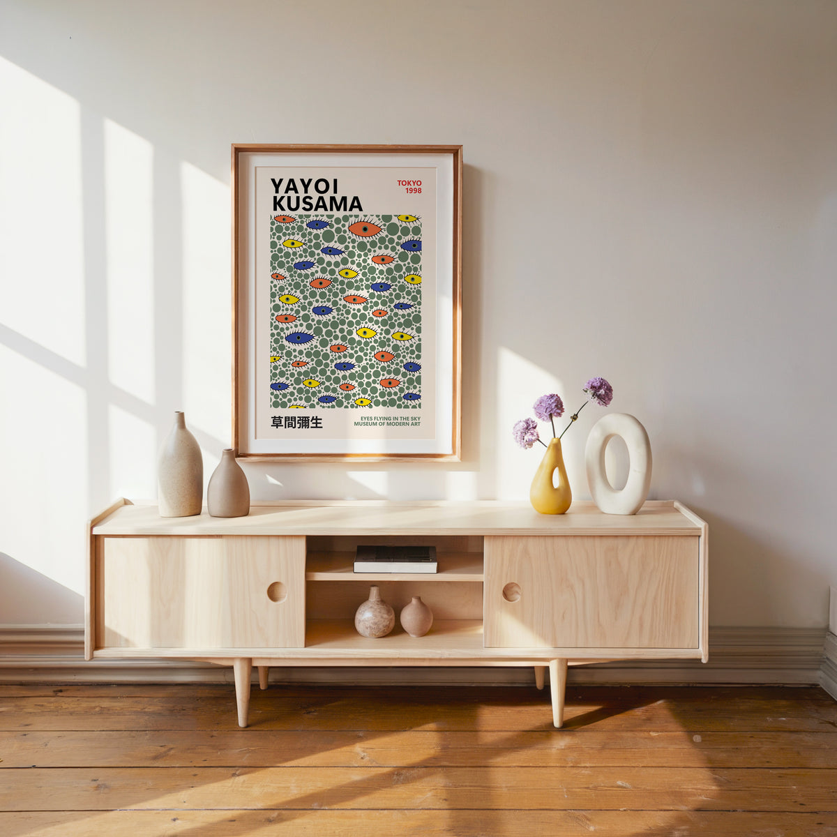 Yayoi Kusama inspired green dots and eyes print above a pale wood console