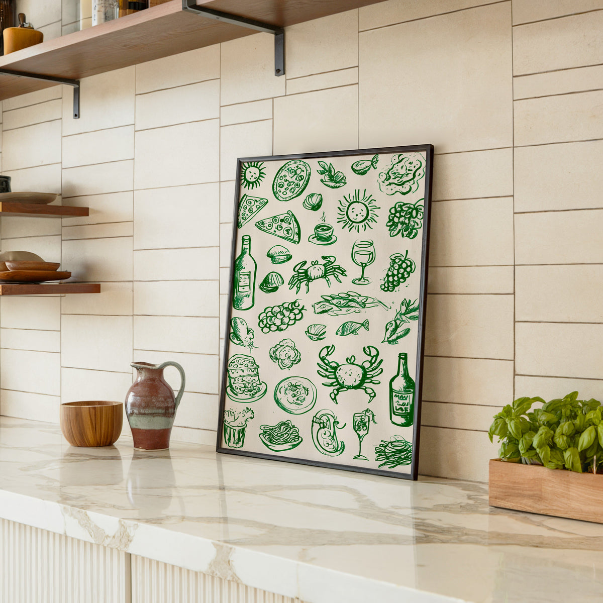 Green food doodle print in a black frame leaning on a marble counter in a tiled kitchen