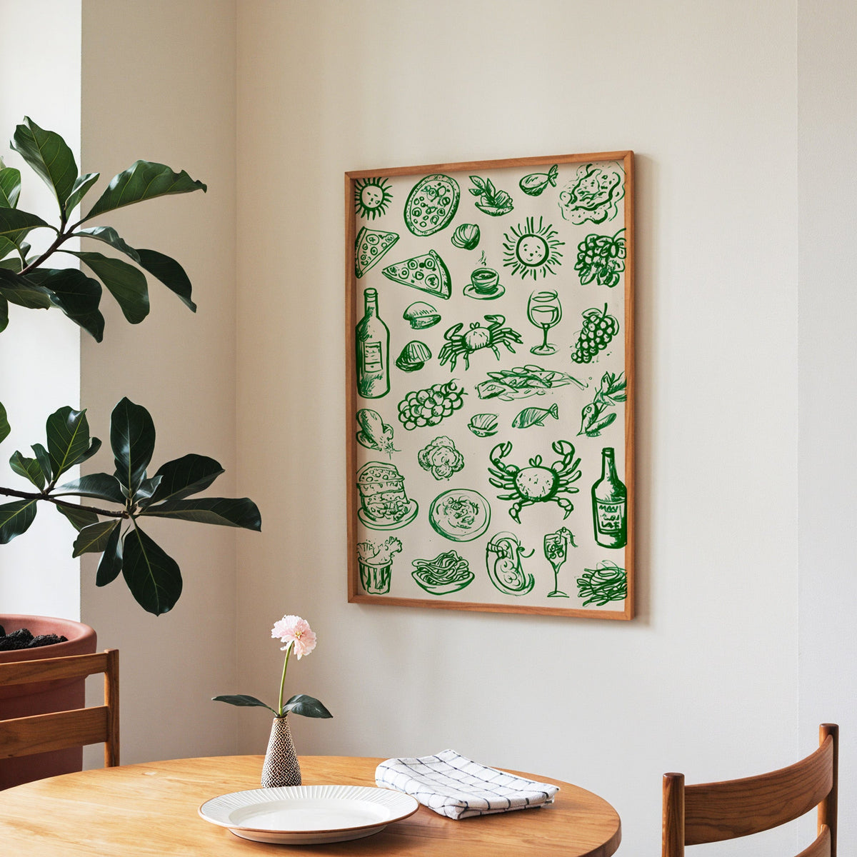Green food doodle print in a walnut frame above a round table beside a fiddle-leaf fig