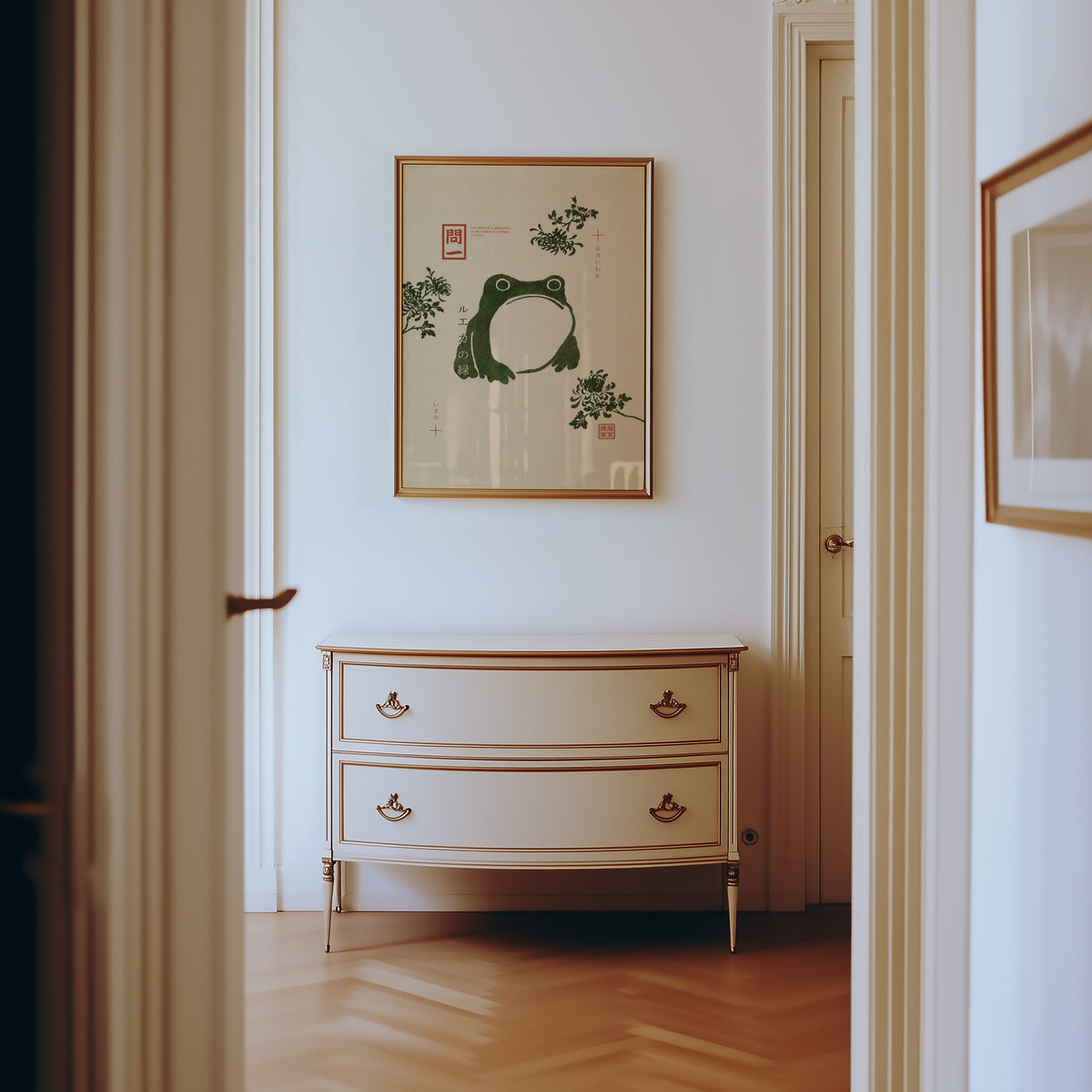 green frog with chrysanthemums print shown in a gold frame in a hallway above a cream dresser