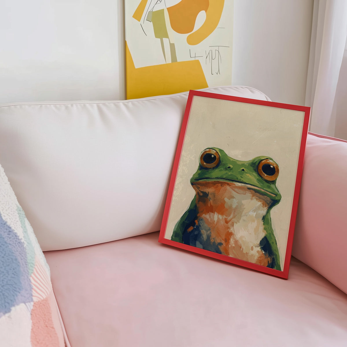 Frog portrait wall art print shown in a red frame leaning on a blush pink sofa